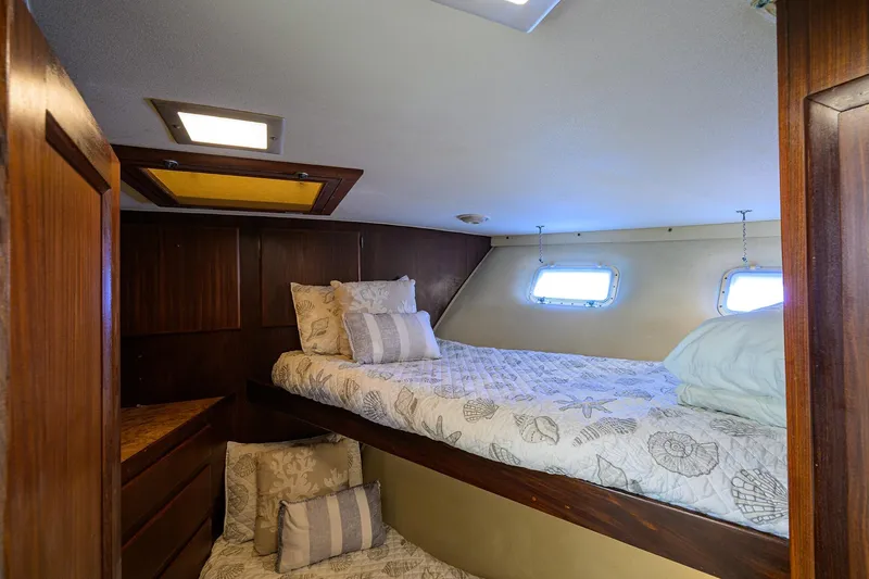 Phantom Yacht Photos Pics Cozy cabin interior of 1987 Hatteras 63 Motor Yacht with wooden accents and bedding.