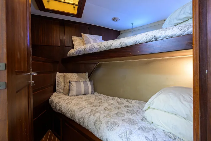 Phantom Yacht Photos Pics Cozy bunk beds in 1987 Hatteras 63 Motor Yacht cabin with nautical-themed bedding.