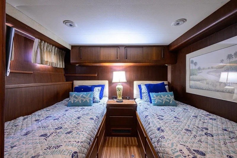 Phantom Yacht Photos Pics Cozy twin cabin in 1987 Hatteras 63 Motor Yacht with nautical decor and warm lighting.