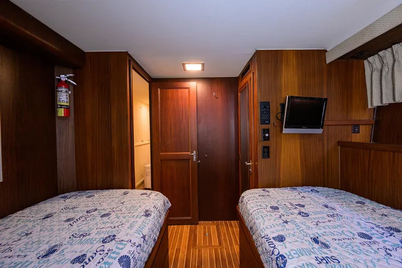 Phantom Yacht Photos Pics Interior of 1987 Hatteras 63 Motor Yacht with twin beds and wooden paneling.