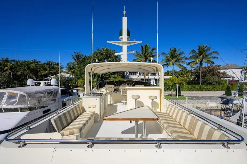 Phantom Yacht Photos Pics 1987 Hatteras 63 Motor Yacht with spacious deck, docked near palm trees under clear blue sky.