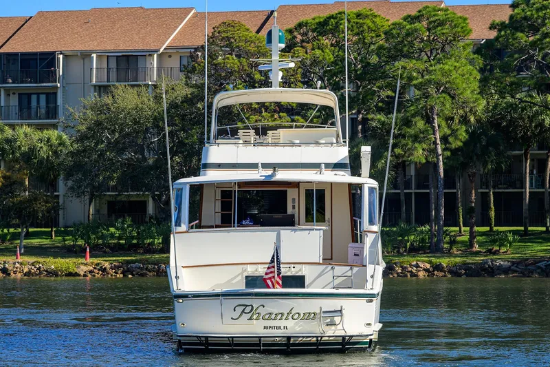Phantom Yacht Photos Pics 1987 Hatteras 63 Motor Yacht on water, trees and buildings in background.