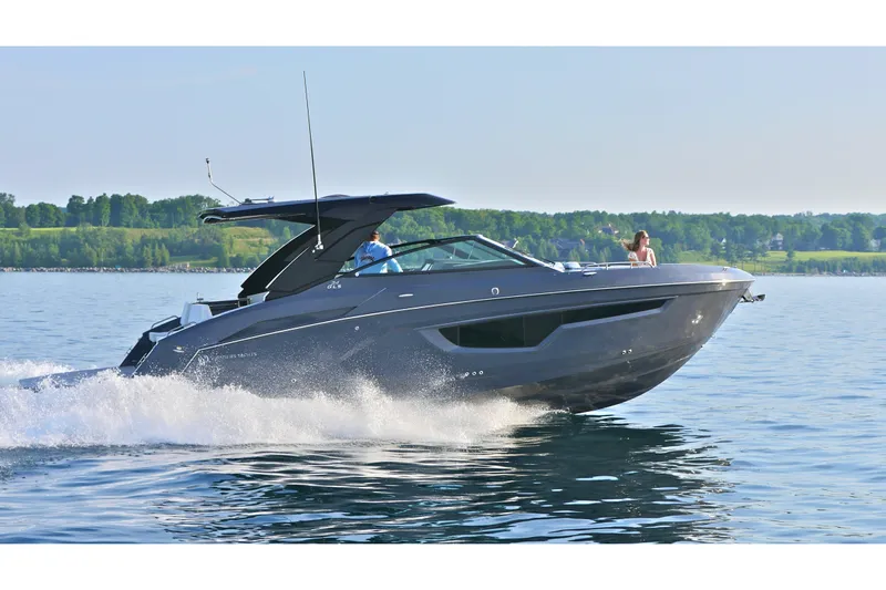  Yacht Photos Pics 2026 Cruisers Yachts 34 GLS I/O cruising on a serene lake with lush green shoreline.