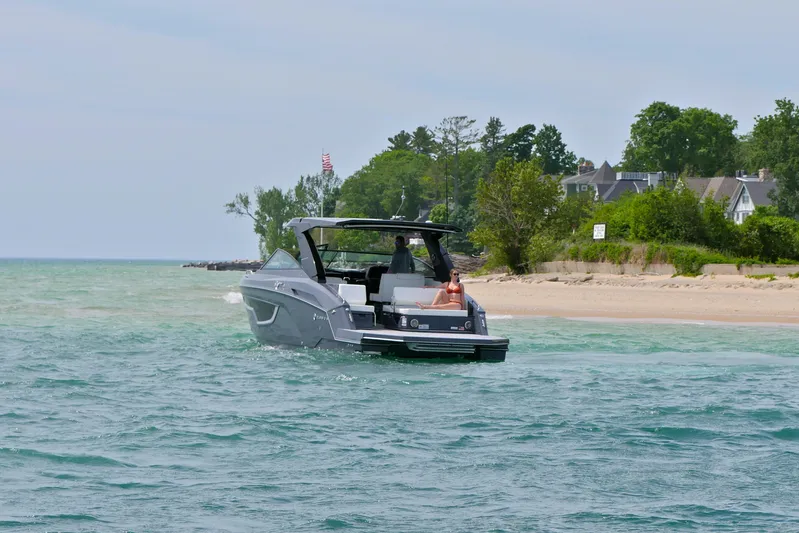  Yacht Photos Pics 2026 Cruisers Yachts 34 GLS I/O on serene waters near a sandy beach.