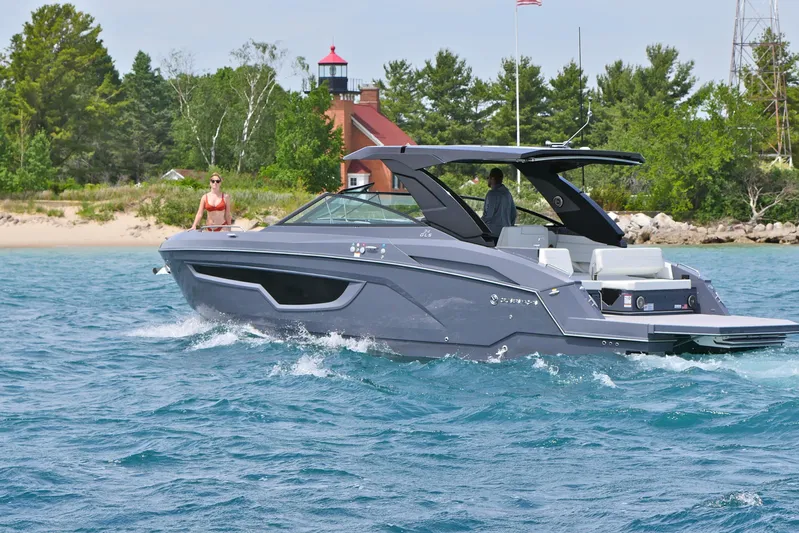  Yacht Photos Pics 2026 Cruisers Yachts 34 GLS I/O on water near a lighthouse and trees.