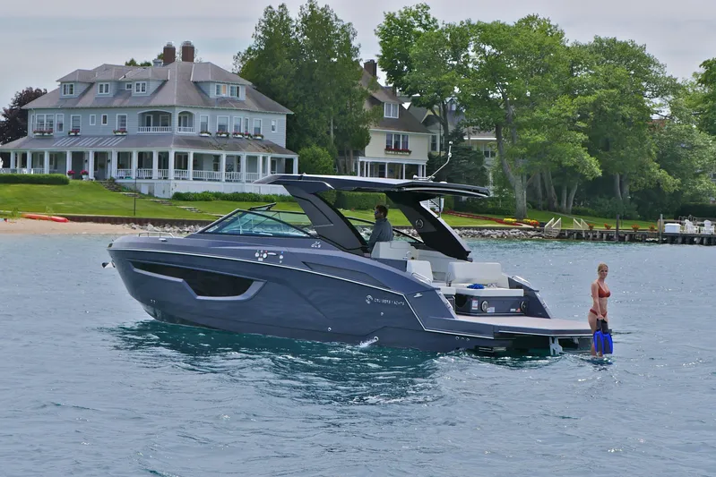  Yacht Photos Pics 2026 Cruisers Yachts 34 GLS I/O near waterfront homes, with a person swimming nearby.