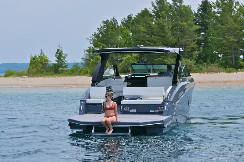  Yacht Photos Pics 2026 Cruisers Yachts 34 GLS I/O on water, woman relaxing, scenic beach backdrop.