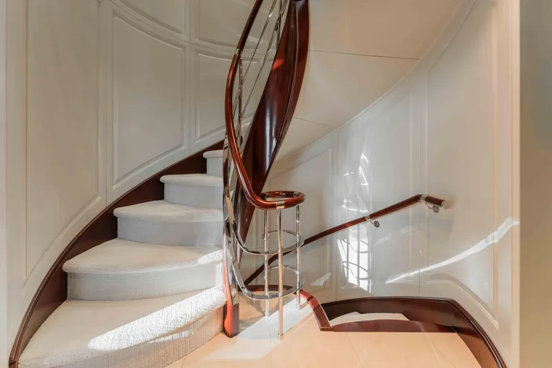 Summerdance Yacht Photos Pics Elegant spiral staircase on 2004 Trinity Yachts motor yacht, featuring polished wood and plush carpeting.