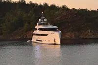 Luxurious 2014 Bilgin Custom 150 yacht anchored near a scenic, wooded shoreline at sunset.