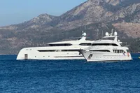 Luxury yachts, including a 2014 Bilgin Custom 150, anchored near scenic mountains.