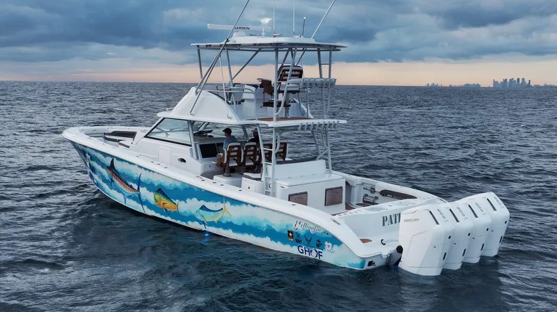  Yacht Photos Pics 2022 Yellowfin 54 Offshore boat on ocean, vibrant fish graphics, overcast sky.