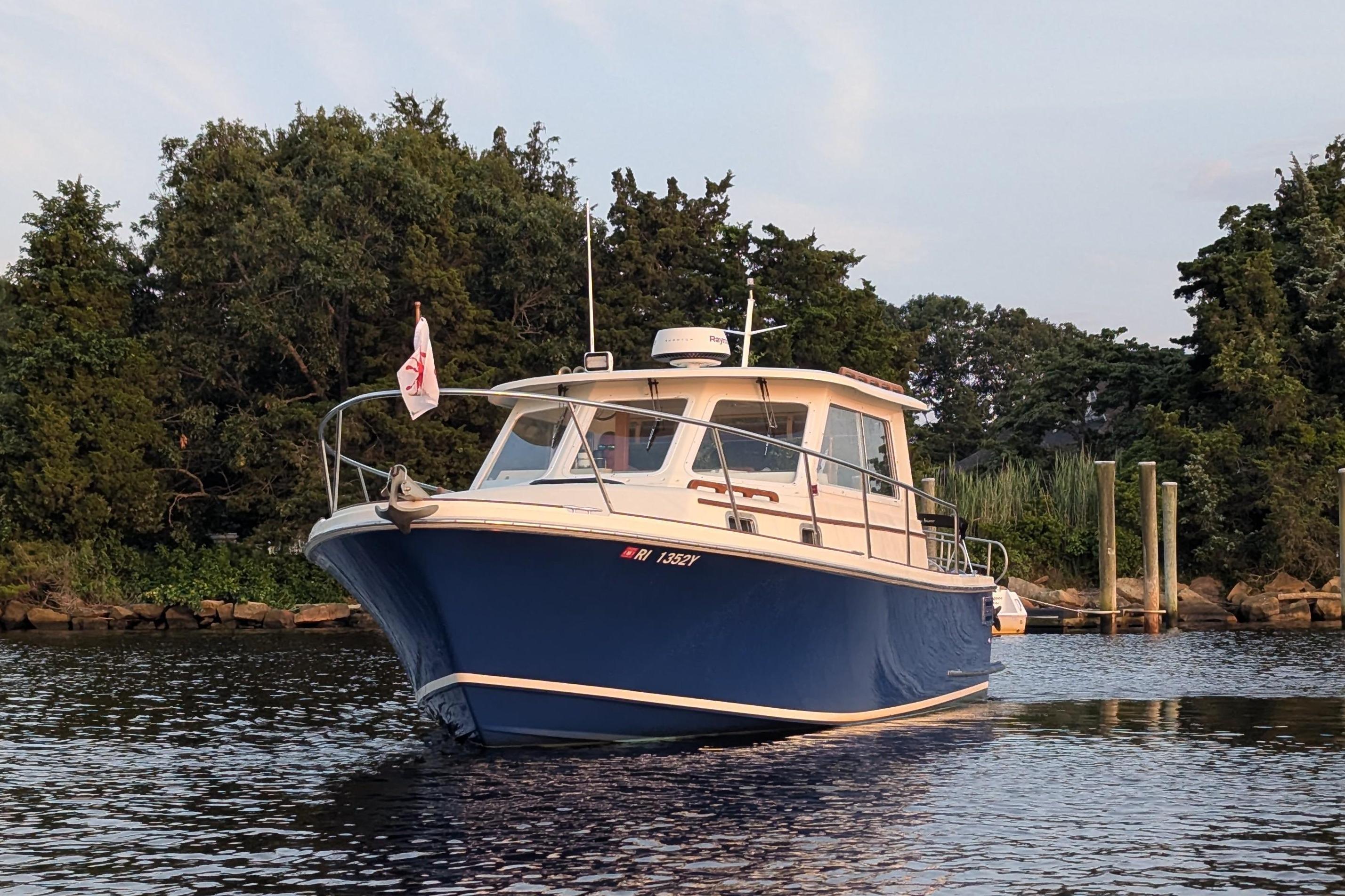 Hunt Yachts 28 Express 2000 model on calm water near a wooded shoreline.