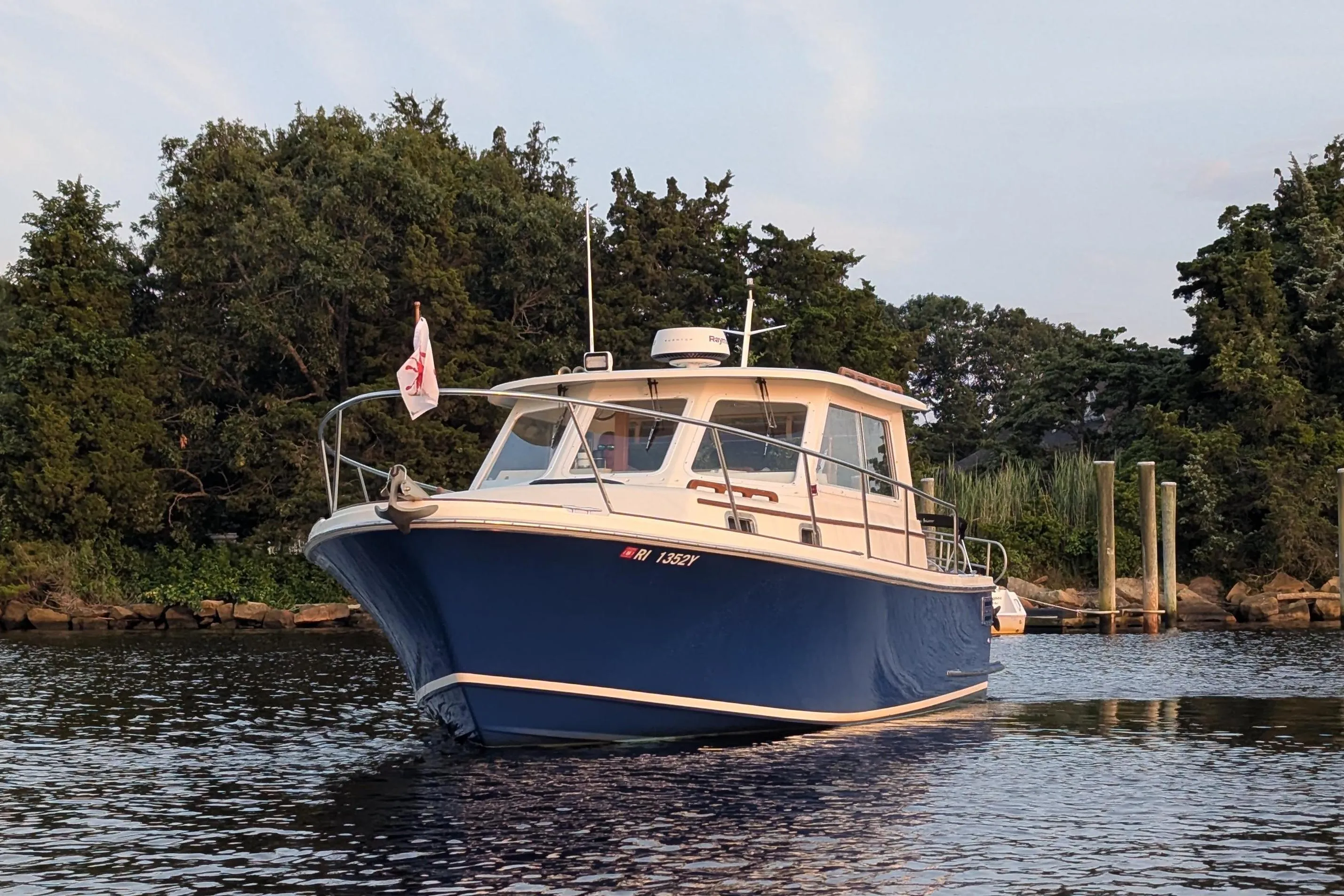 Hunt Yachts 28 Express 2000 model on calm water near a wooded shoreline.