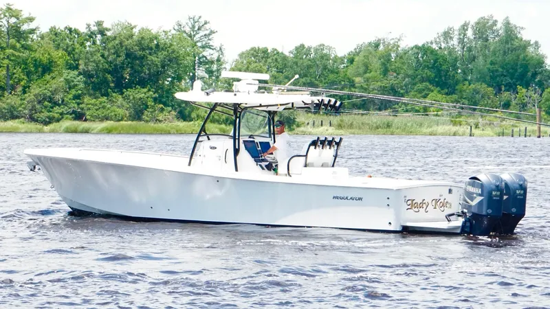  Yacht Photos Pics 2014 Regulator 34 boat on water with dual Yamaha engines, surrounded by lush greenery.