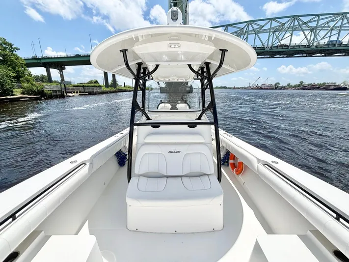  Yacht Photos Pics 2014 Regulator 34 boat on water near a bridge, clear sky, and lush greenery.
