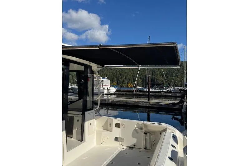  Yacht Photos Pics 2020 Boston Whaler 325 Conquest at marina, featuring spacious deck and canopy under blue sky.