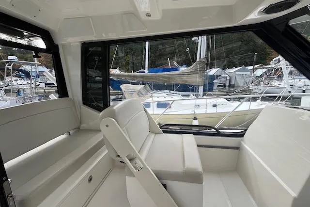  Yacht Photos Pics Interior of a 2020 Boston Whaler 325 Conquest boat, featuring white seating and marina view.