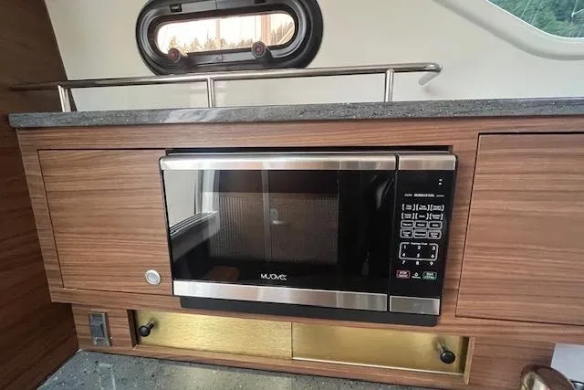  Yacht Photos Pics 2020 Boston Whaler 325 Conquest interior with built-in microwave and wood cabinetry.