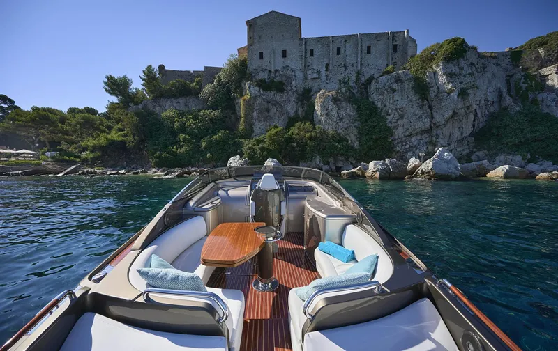  Yacht Photos Pics Luxurious 2014 Riva Rivarama Super 44 yacht near rocky coastline and historic building.