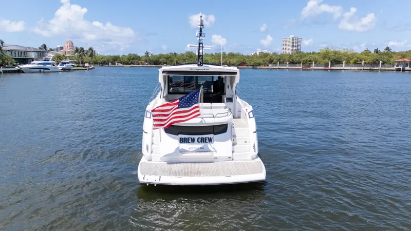 Brew Crew Yacht Photos Pics Sunseeker Predator 60 yacht, 2022 model, with American flag, on a sunny waterway.