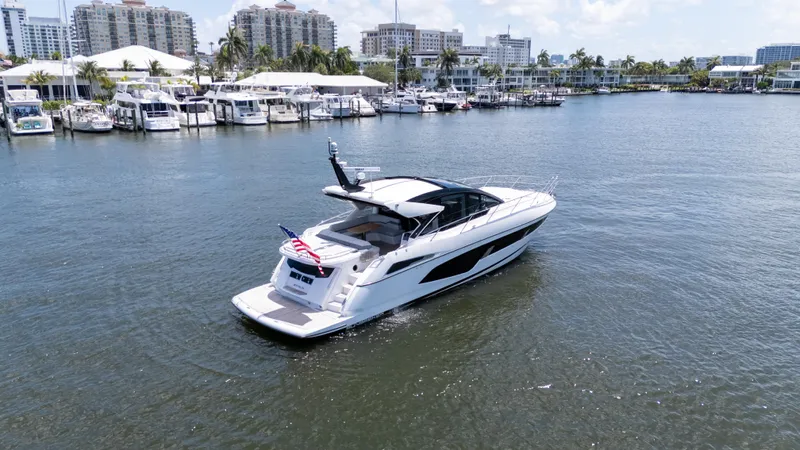 Brew Crew Yacht Photos Pics 2022 Sunseeker Predator 60 yacht cruising in a marina with cityscape background.
