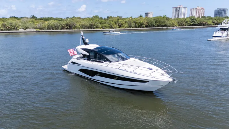 Brew Crew Yacht Photos Pics 2022 Sunseeker Predator 60 yacht cruising on a scenic waterway with city skyline backdrop.