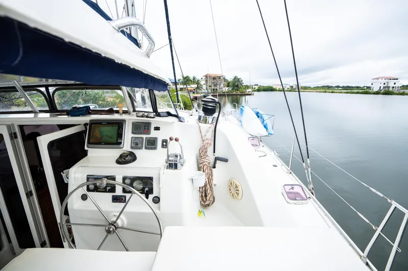 Dreaming On Yacht Photos Pics 2003 Leopard 47 yacht cockpit with steering wheel and navigation equipment, docked by a serene waterfront.