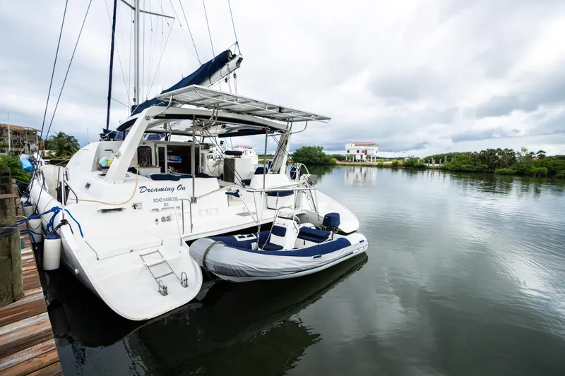 Dreaming On Yacht Photos Pics Leopard 47 catamaran docked by calm waters, 2003 model, with inflatable dinghy attached.