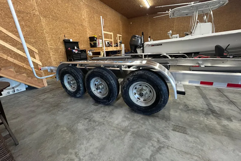  Yacht Photos Pics Trailer with triple axles in a garage, next to a boat.