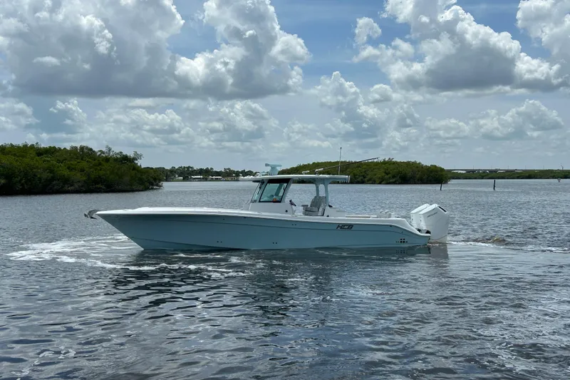  Yacht Photos Pics 2023 HCB 39 Speciale boat cruising on a calm, scenic waterway under a cloudy sky.