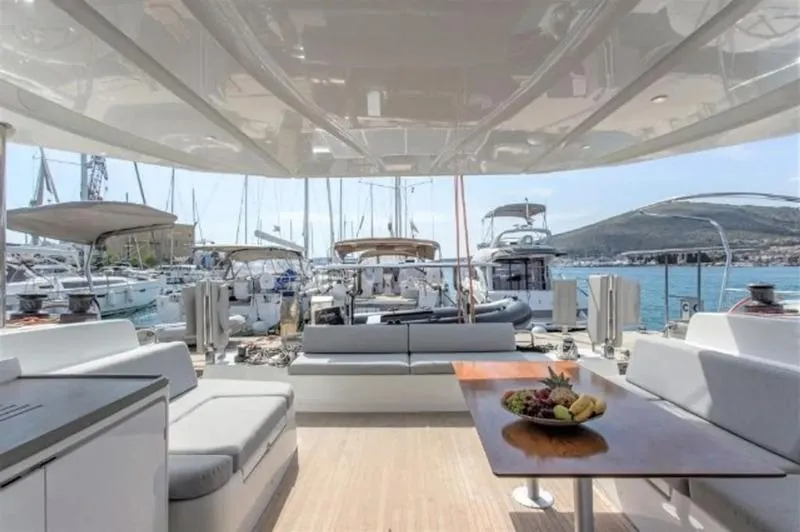 Tranquillity Yacht Photos Pics Luxurious 2022 Excess 15 yacht interior with elegant seating and table, docked at a marina.