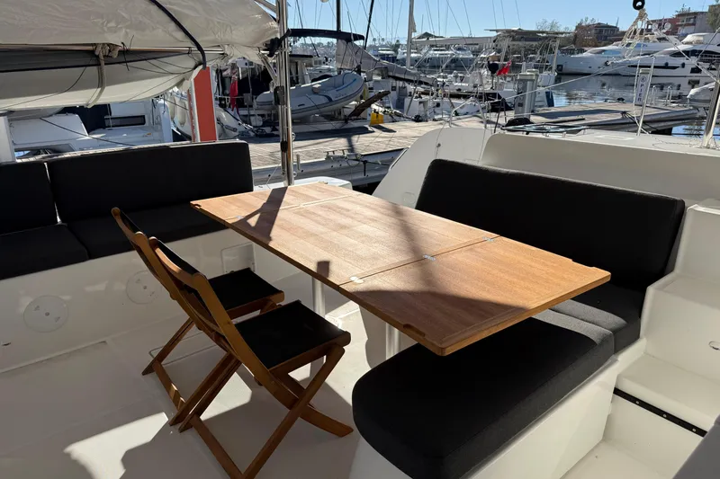  Yacht Photos Pics Outdoor seating area on a 2022 Lagoon 46 yacht, featuring a wooden table and chairs.