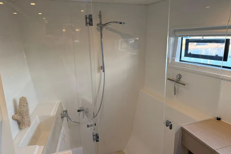  Yacht Photos Pics Modern bathroom interior of 2022 Lagoon 46 yacht with shower and window.