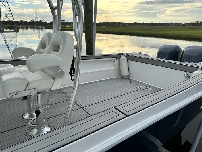  Yacht Photos Pics Custom Shark Fin R321 boat deck with white seating, overlooking serene water and grassy shoreline.