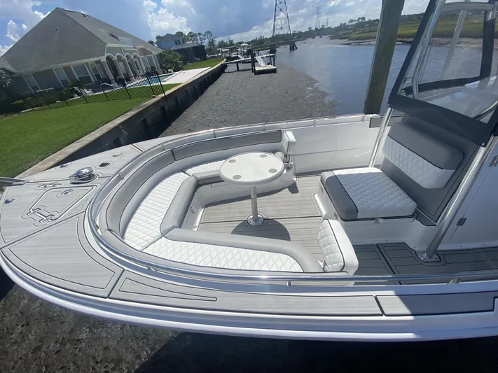  Yacht Photos Pics Luxurious 2023 Custom Shark Fin R321 boat with elegant seating and table, docked by a canal.