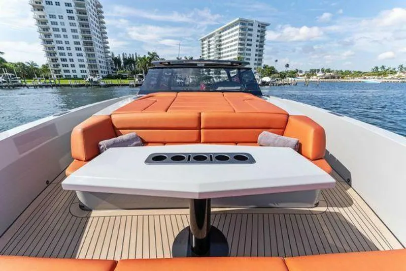 Incentivized Yacht Photos Pics Vanquish VQ58 2021 luxury yacht with orange seating and table, docked near waterfront buildings.