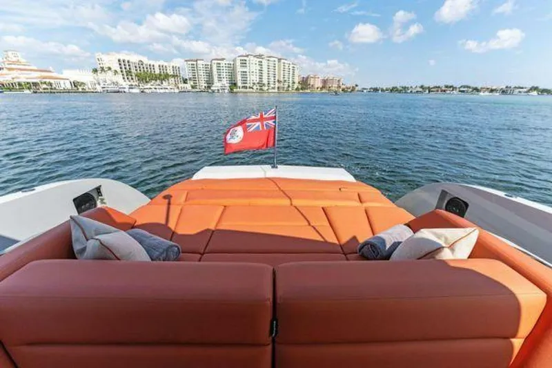 Incentivized Yacht Photos Pics Luxury Vanquish VQ58 yacht with orange seating, scenic waterfront view, and red flag.