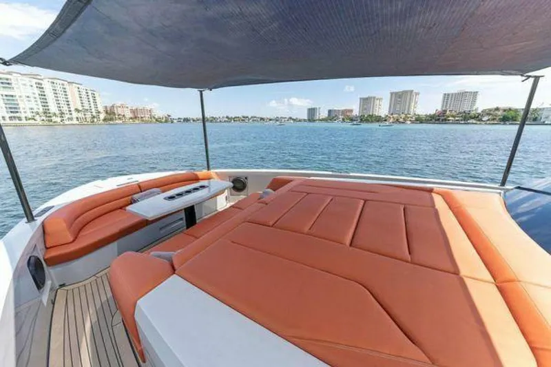 Incentivized Yacht Photos Pics Luxurious 2021 Vanquish VQ58 yacht with orange seating, shaded deck, and waterfront city view.