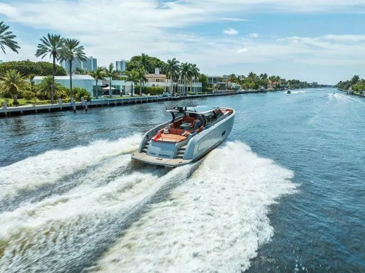 Incentivized Yacht Photos Pics Luxury Vanquish VQ58 yacht cruising on a scenic waterway, surrounded by palm trees.