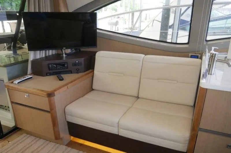 Necessity Yacht Photos Pics Interior of 2017 Sea Ray Fly 400 yacht with beige sofa and mounted TV.
