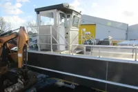 2023 Robust LC1227 boat with cabin, docked near industrial equipment and buildings.