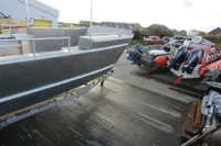 Boat yard with Robust LC1227 model, 2023, alongside other vessels on a concrete surface.