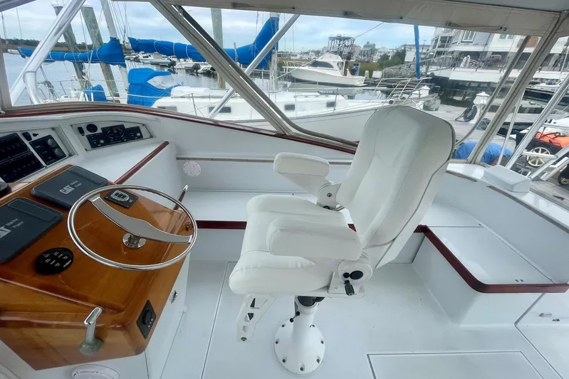 M.a.c. Daddy Yacht Photos Pics Helm of 2005 Custom DeSanti Carolina Express boat with white captain's chair and wooden dashboard.