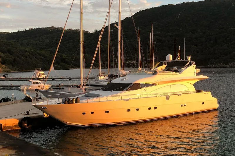  Yacht Photos Pics Luxurious 2003 Mochi 2250 yacht docked at sunset, surrounded by serene waters and lush hills.