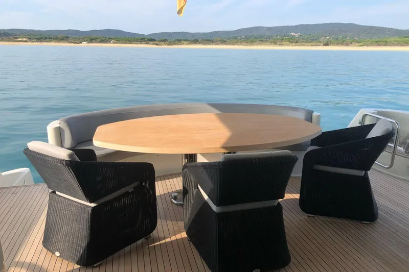  Yacht Photos Pics Luxury yacht deck with round table and chairs, Mochi 2250, 2003 model, scenic ocean view.