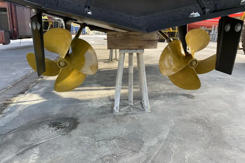  Yacht Photos Pics Dual propellers of a 2003 Mochi 2250 boat on a stand in a shipyard.