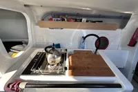 Compact kitchen area in a 2022 Dehler 30 sailboat with stove and wooden cutting board.