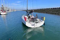 2022 Dehler 30 sailboat navigating a calm marina channel under clear blue skies.