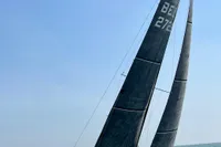 2022 Dehler 30 sailboat navigating on open water under clear blue skies.