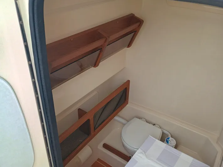  Yacht Photos Pics 2025 Grady-White Canyon 271 boat interior with compact bathroom and wooden shelving.